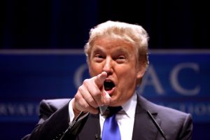 Donald Trump zeigt mit dem rechten Zeigefinger auf den Leser und hat den Mund geöffnet, guckt böse